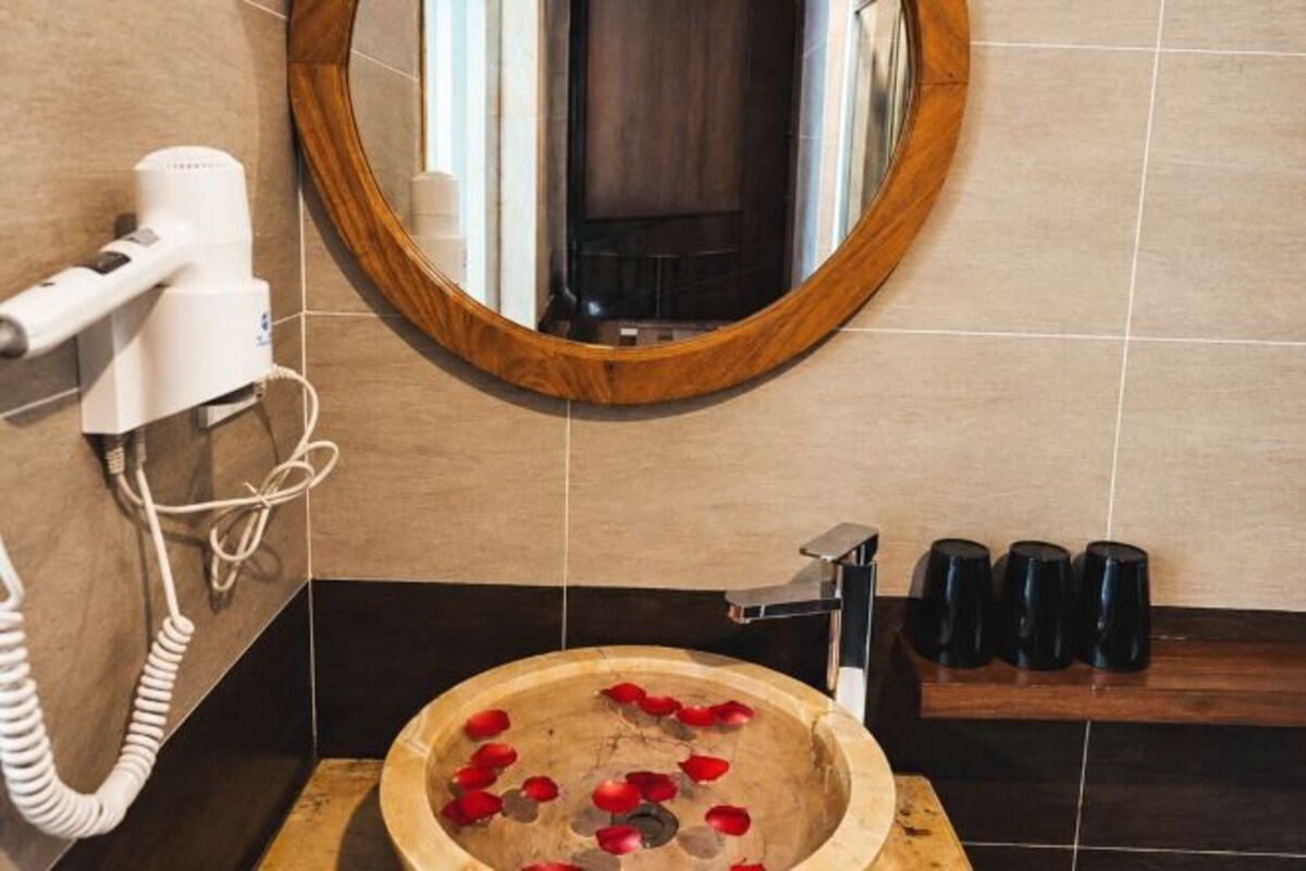 Ein Badezimmer mit Föhn, Spiegel und Waschbecken aus Holz mit roten Blumen.