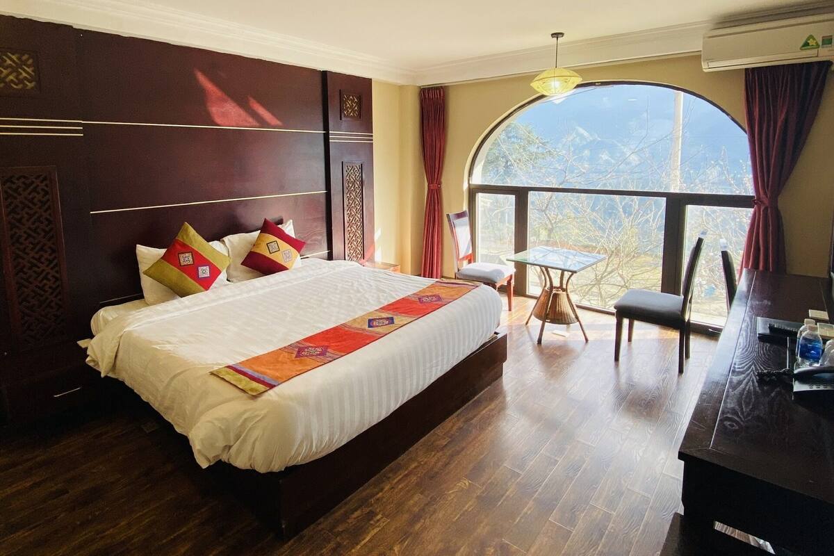 Een hotelkamer met een groot bed, een bureau en uitzicht op de omgeving.
