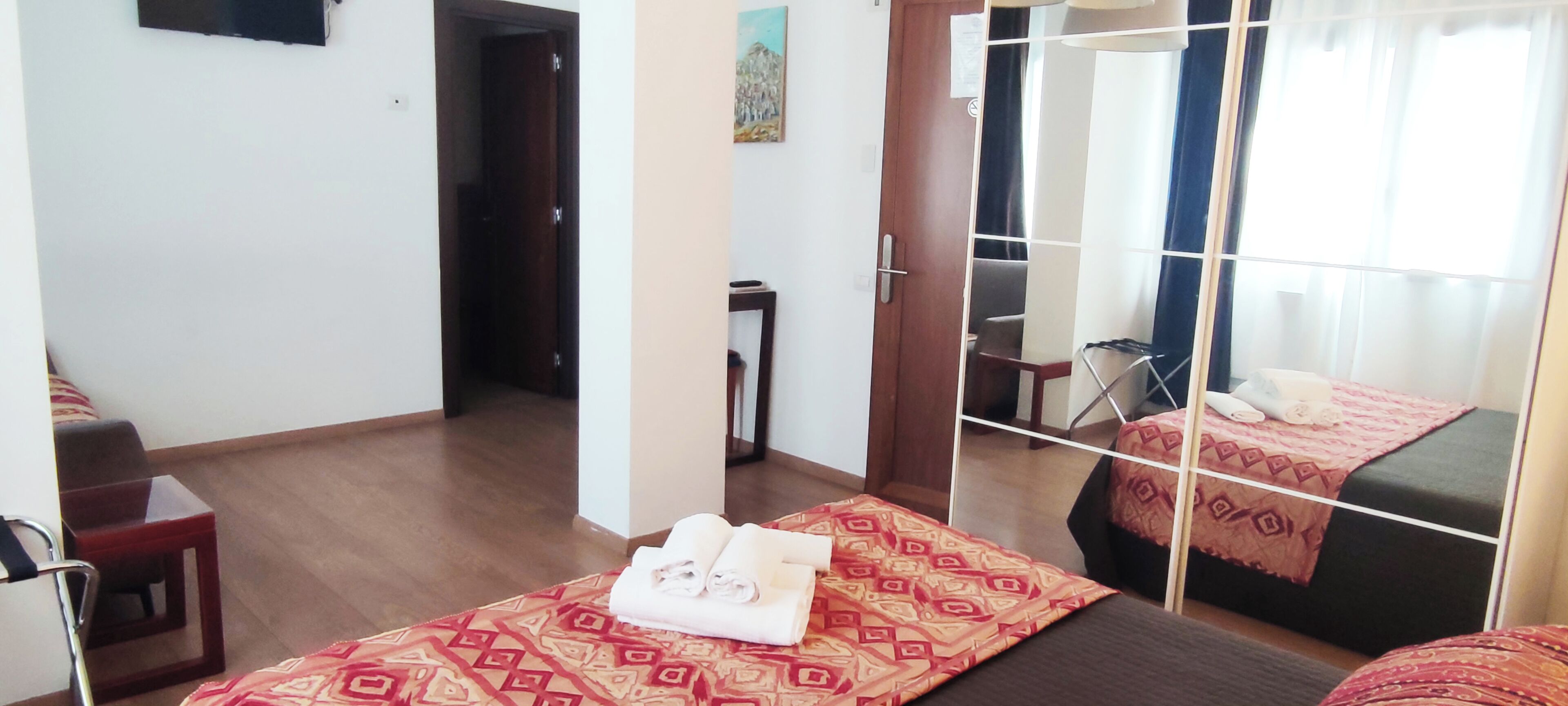 Una camera d'albergo con un letto, una sedia, un tavolino e uno specchio.