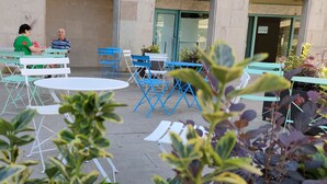 An outdoor seating area with tables and chairs, a building entrance, and potted plants. - Piazza Mulino 26 (Matera)