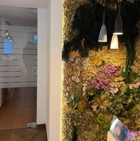 Un muro con giardino verticale, due lampade a sospensione e un poster su un cavalletto.