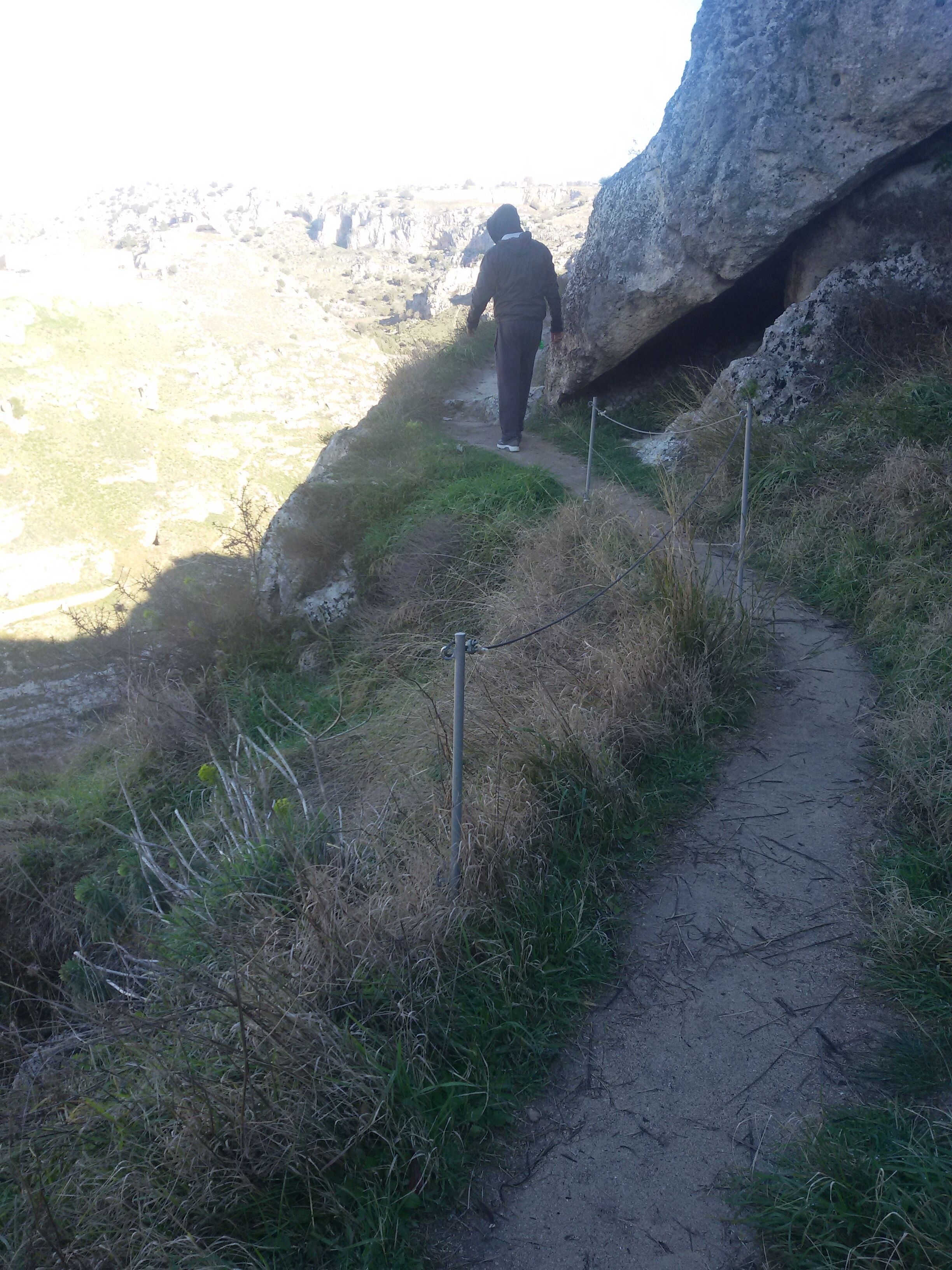 A narrow dirt path leading to a rocky cliff.