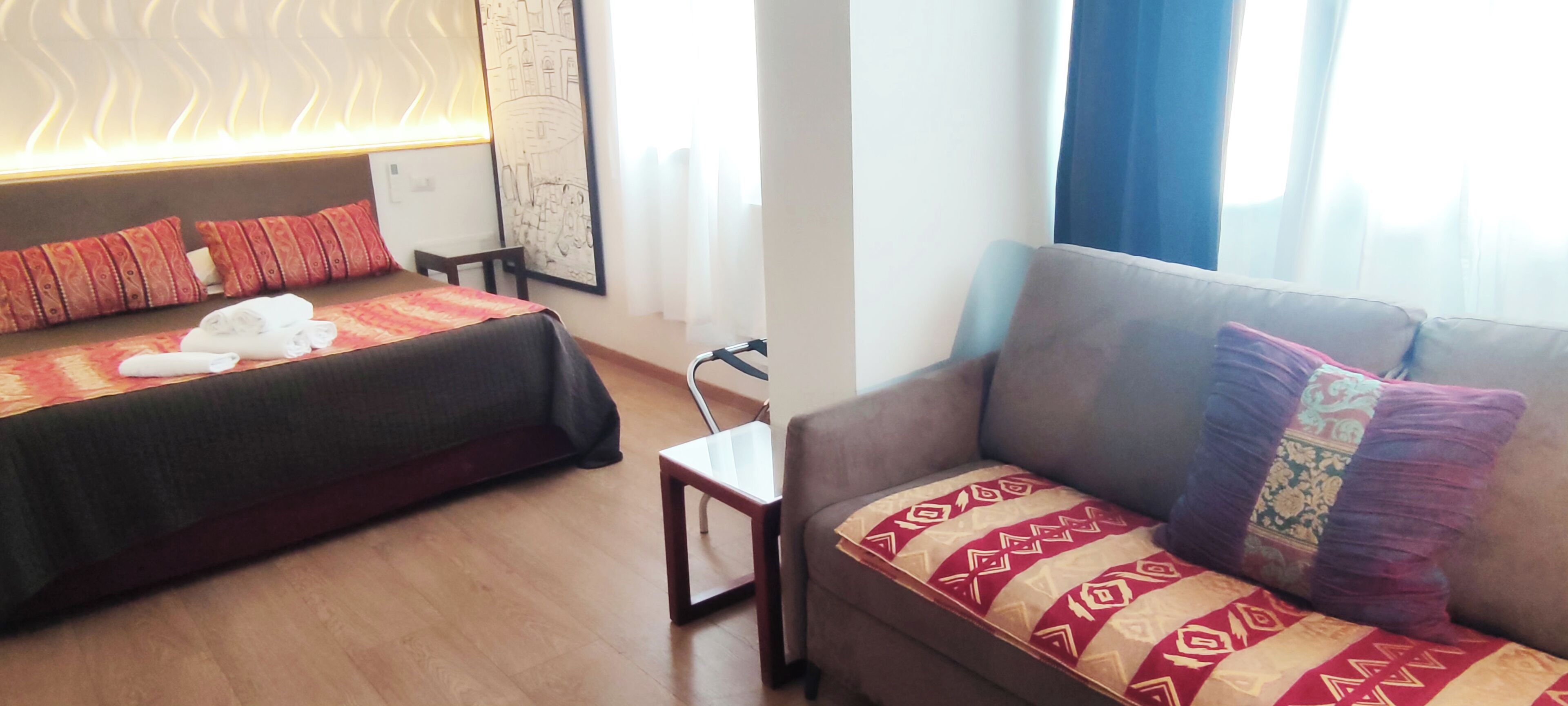 A hotel room with two beds, a sofa, and a small table.