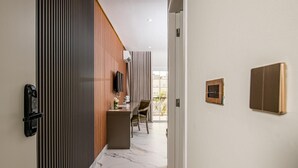 A modern hotel corridor with a wooden panel wall, a marble floor, a seating area with a table and chairs, and a door with a security panel. - Hotel Florença (Luanda)