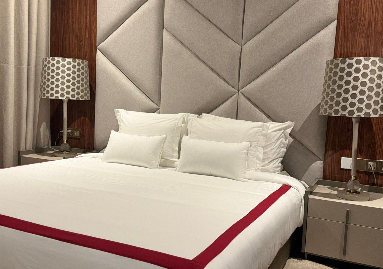 A hotel room with a large bed, two bedside tables, and a headboard with a geometric pattern.