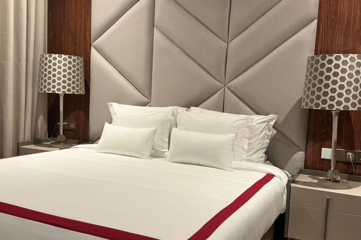 A hotel room with a large bed, two bedside tables, and a headboard with a geometric pattern.