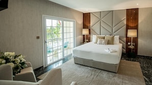 A modern bedroom with a large bed, two bedside lamps, a view through a sliding glass door, and a marble floor. - Hotel Florença (Luanda)