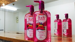 Two bottles of Body Essence Pink Passion Mango body wash on a wooden counter. - The Evergreen Hostel (Hiroshima)