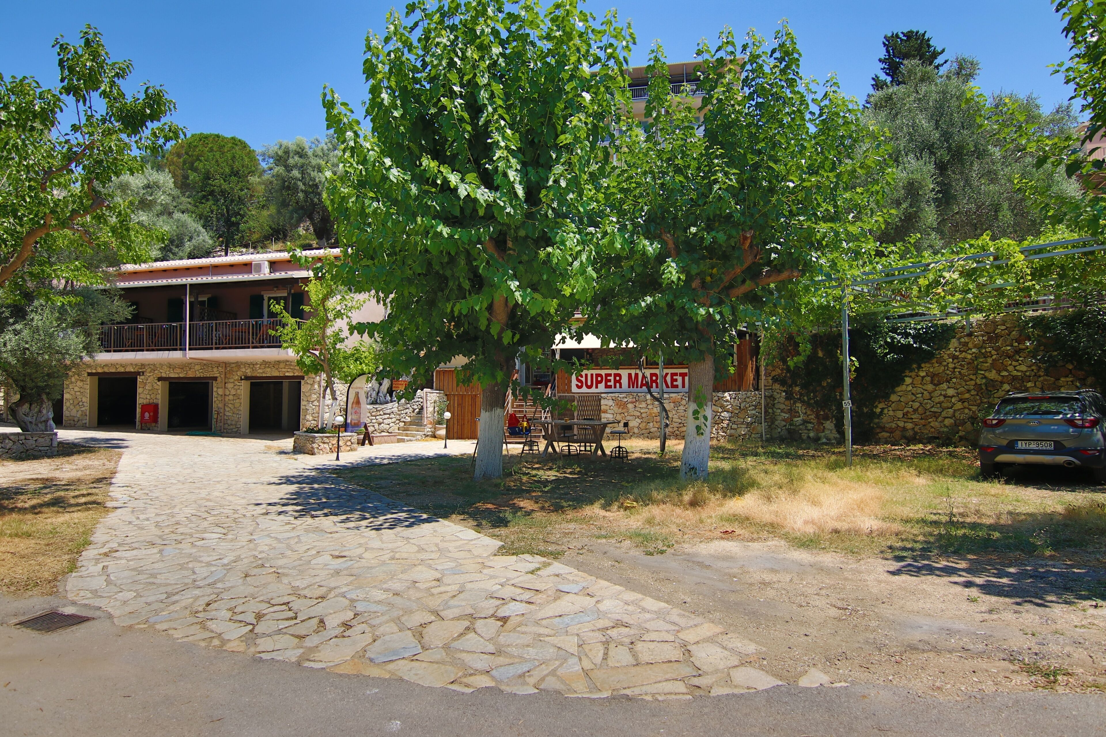 A stone pathway leading to a building with a sign reading "SUPER MARKET".