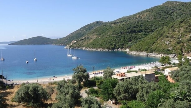 A coastal area with boats on the water, a beach, and a hillside with vegetation. - Poros Beach (Lefkada)