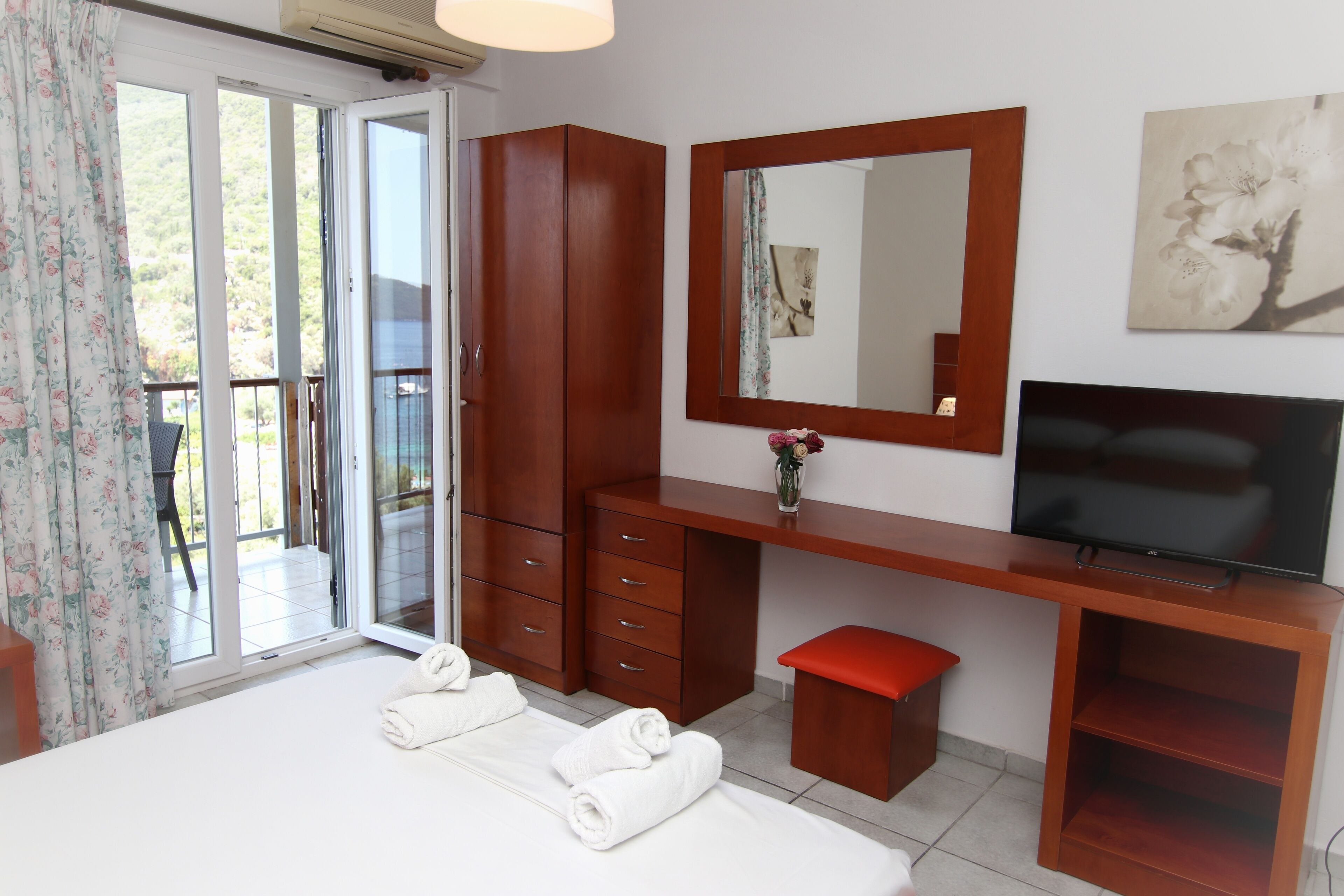 A hotel room with a bed, a TV, a desk, and a bathroom.