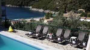 A poolside area with lounge chairs and a view of a coastal landscape. - Poros Beach (Lefkada)