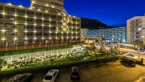 Ein modernes Hotel mit mehreren Etagen, einem Parkplatz und einem angelegten Garten.