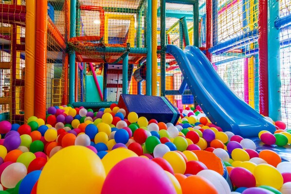 A colorful indoor play area with multiple slides and a ball pit filled with multicolored balls. - Hotel Panorama (Torroella de Montgrí)