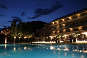 A hotel with a swimming pool, multiple floors, and outdoor lighting.