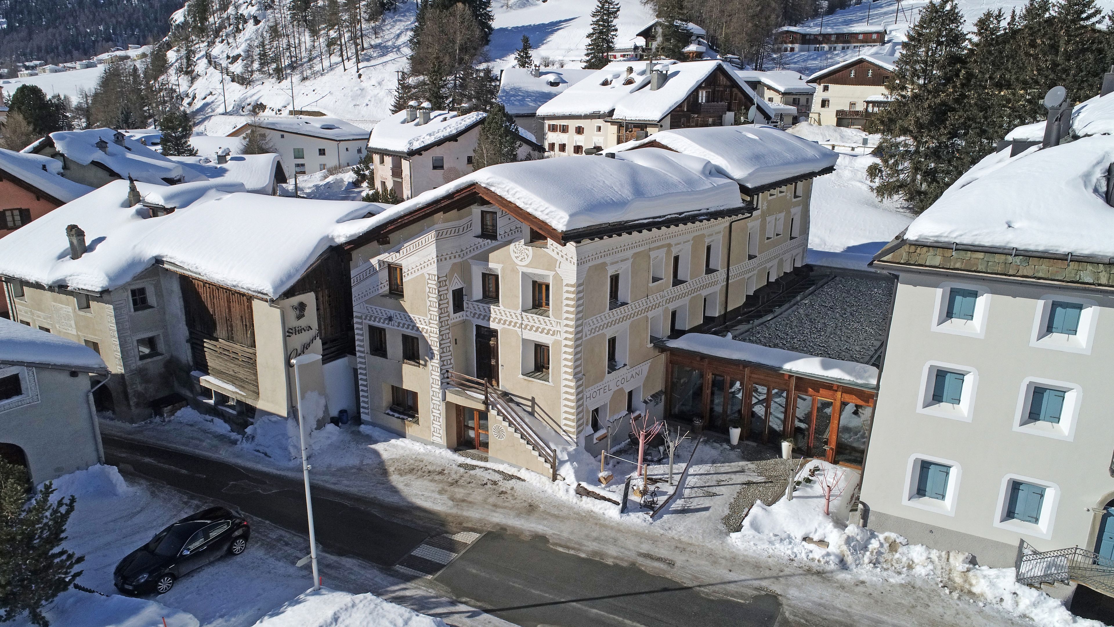 A hotel with a traditional European architectural style, featuring a central courtyard, multiple balconies, and a snow-covered roof.