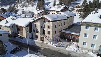 A hotel with a traditional European architectural style, featuring a central courtyard, multiple balconies, and a snow-covered roof.