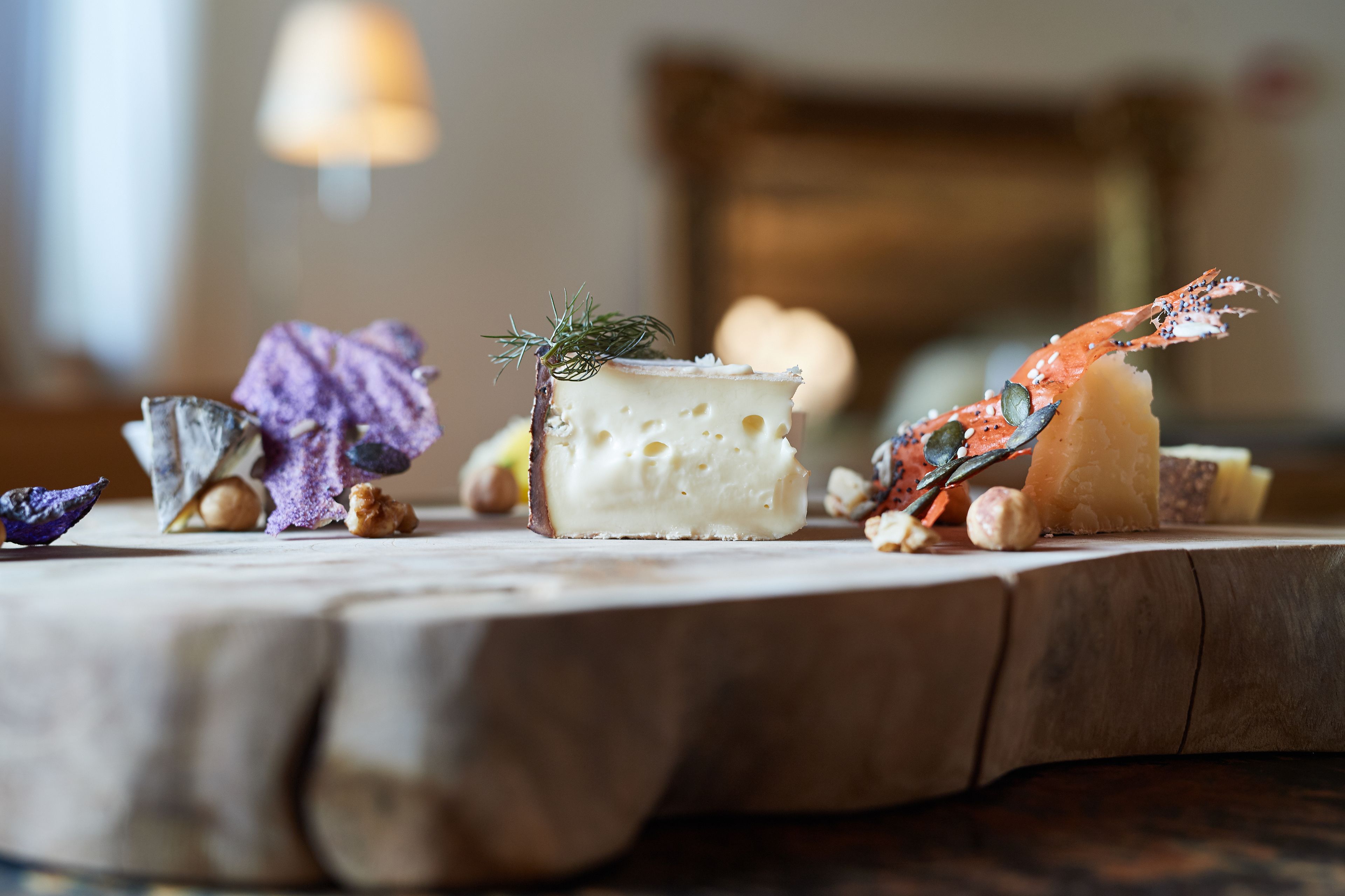 Une table en bois sur laquelle sont disposés divers aliments, notamment du fromage, des noix et une queue de homard.