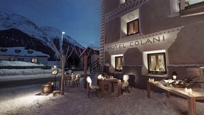 A hotel named "HOTEL COLANI" with outdoor seating and a view of snow-covered mountains. - Chesa Stuva Colani (Madulain)