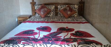 Una cama con una colcha estampada, dos almohadas decorativas y un cabecero de madera.