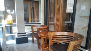 A wooden dining table and chairs in a well-lit room with tiled flooring and large windows. - Rumah Ary Homestay & Spa (Ubud)