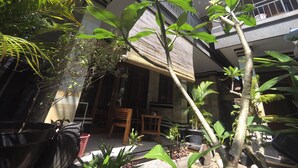A courtyard with potted plants, a wooden chair, and a bamboo screen. - Rumah Ary Homestay & Spa (Ubud)