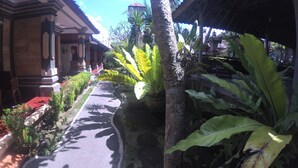A pathway flanked by tropical plants and traditional architecture. - Rumah Ary Homestay & Spa (Ubud)