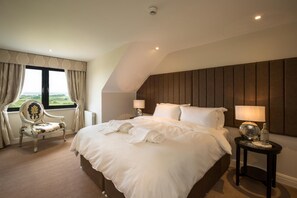 A hotel room with a large bed, two bedside tables, a chair, and a view of the outdoors through a window. - Down Yonder Boutique B&B (Rosses Point)