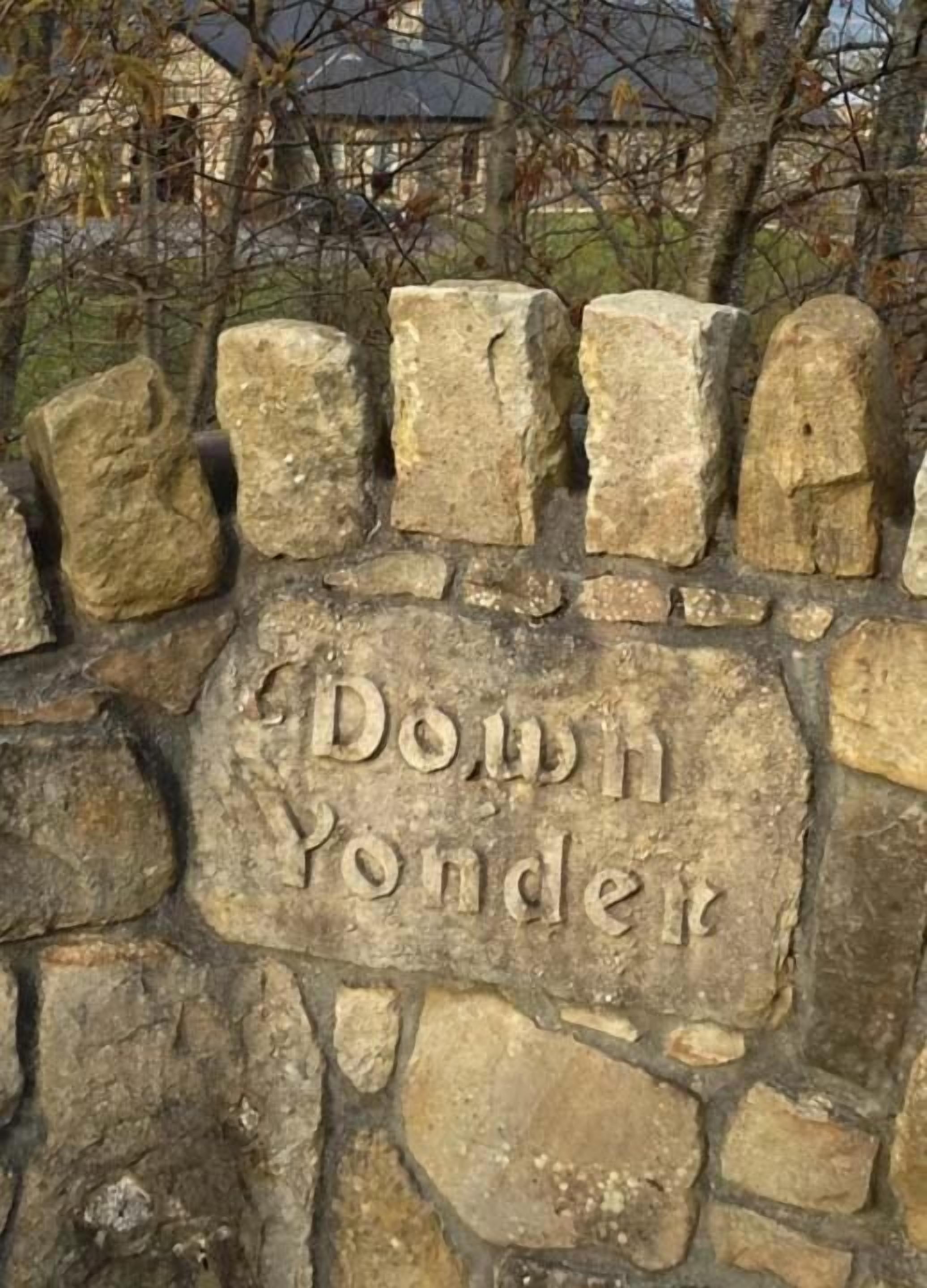 Un muro de piedra con la inscripción "Down Yonder".