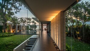 A modern building with a glass facade, a staircase, and a well-maintained garden.