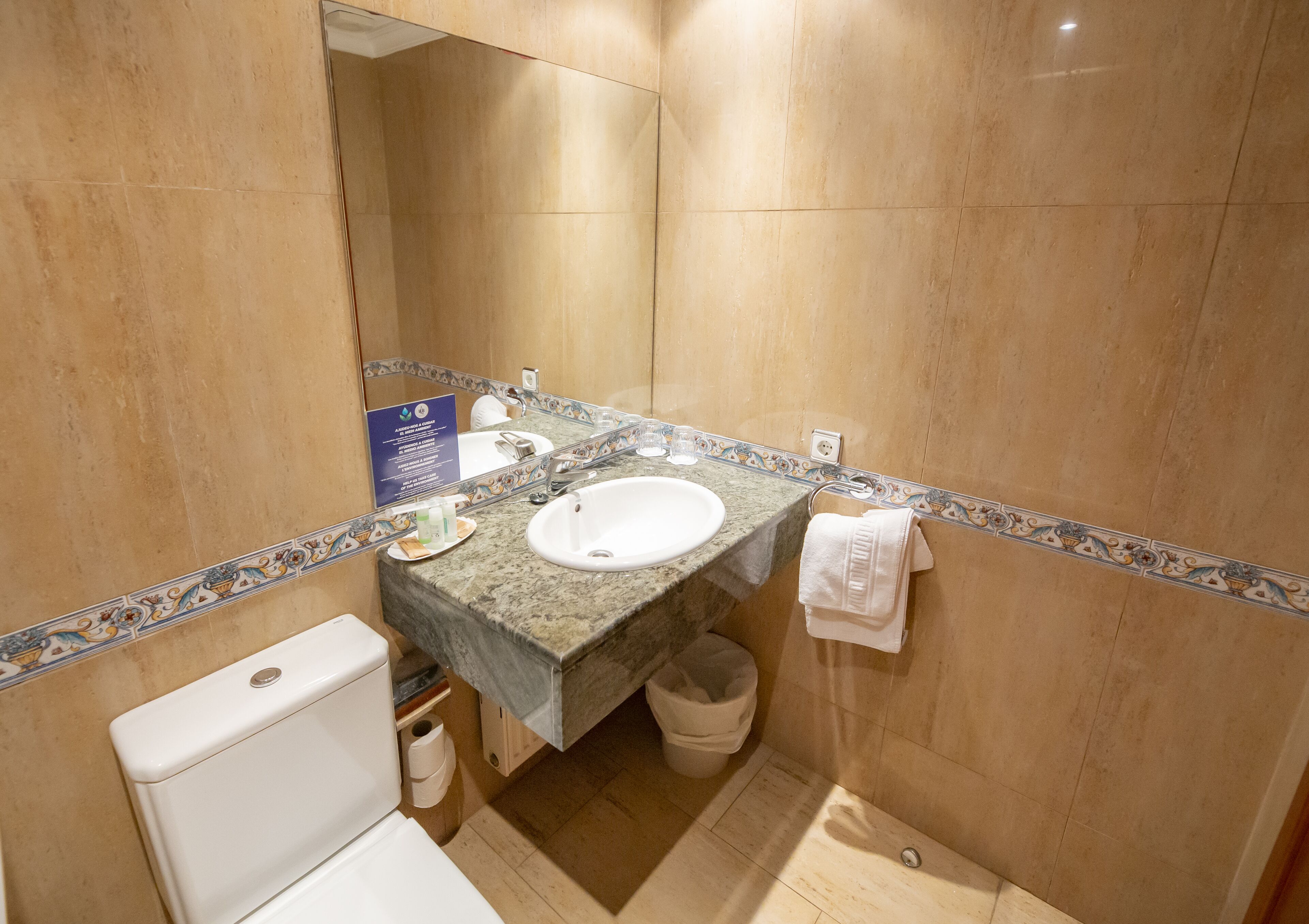 Een badkamer met een marmeren wastafel, toilet en een prullenbak.