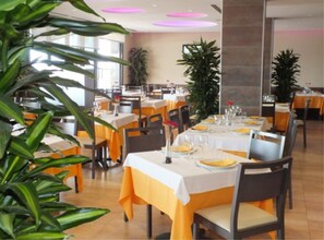 A restaurant with tables set for dining, featuring yellow tablecloths and chairs.