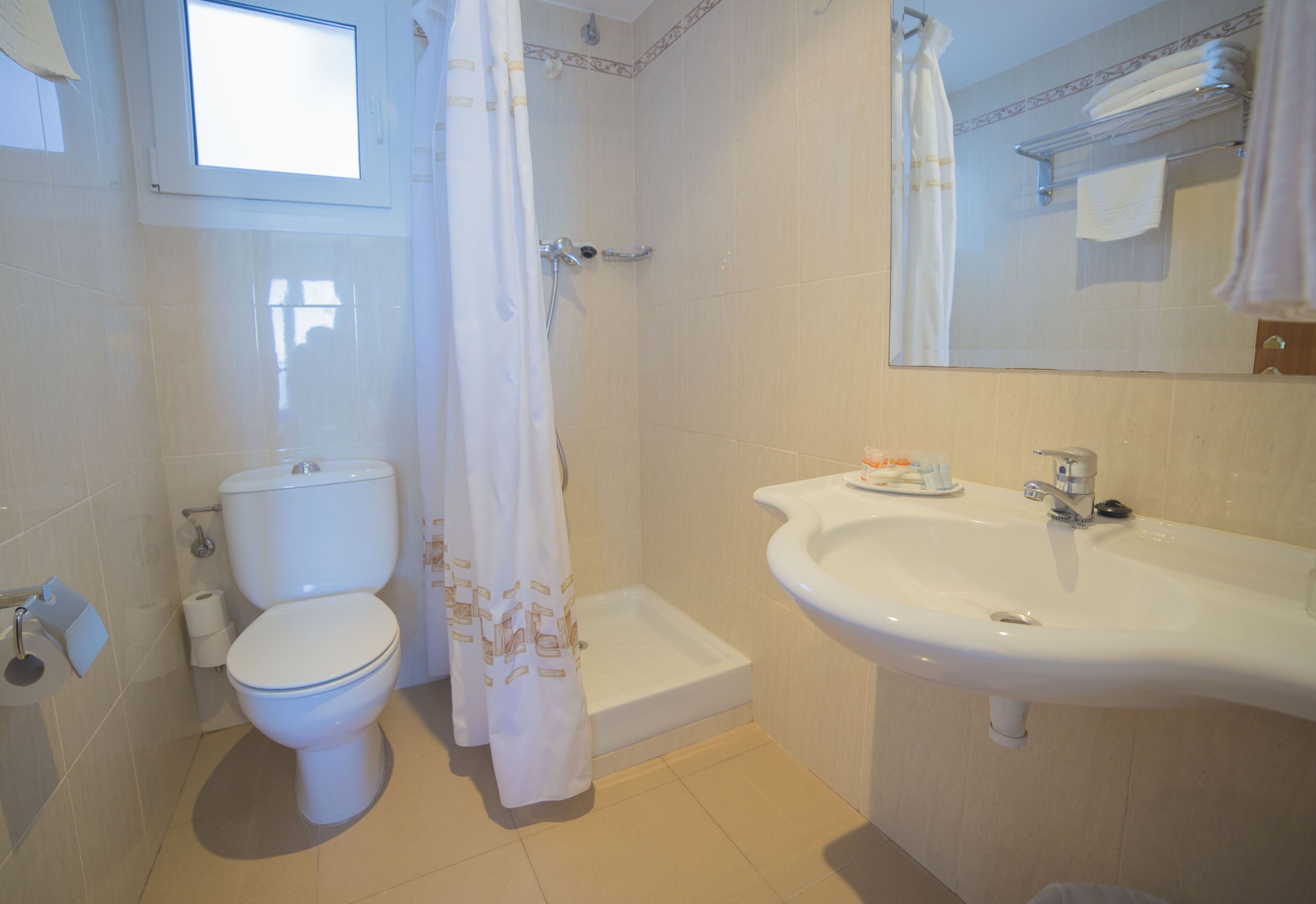 Une salle de bain équipée de toilettes, d’une douche, d’un lavabo et d’un miroir.