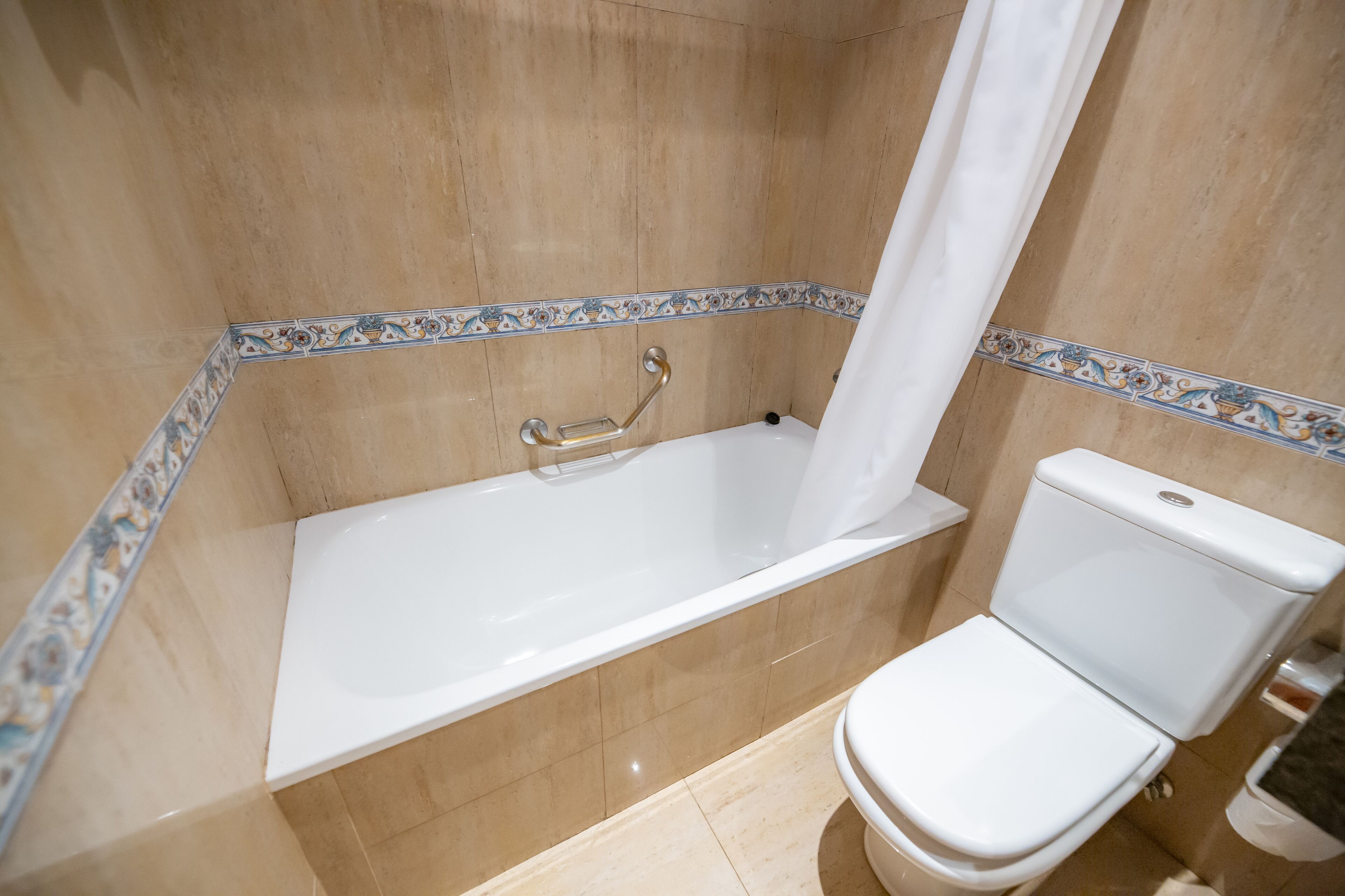 Un baño con bañera, inodoro y cortina de ducha.