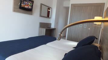 Habitación de hotel con cama, televisión montada en la pared, espejo y lámpara.