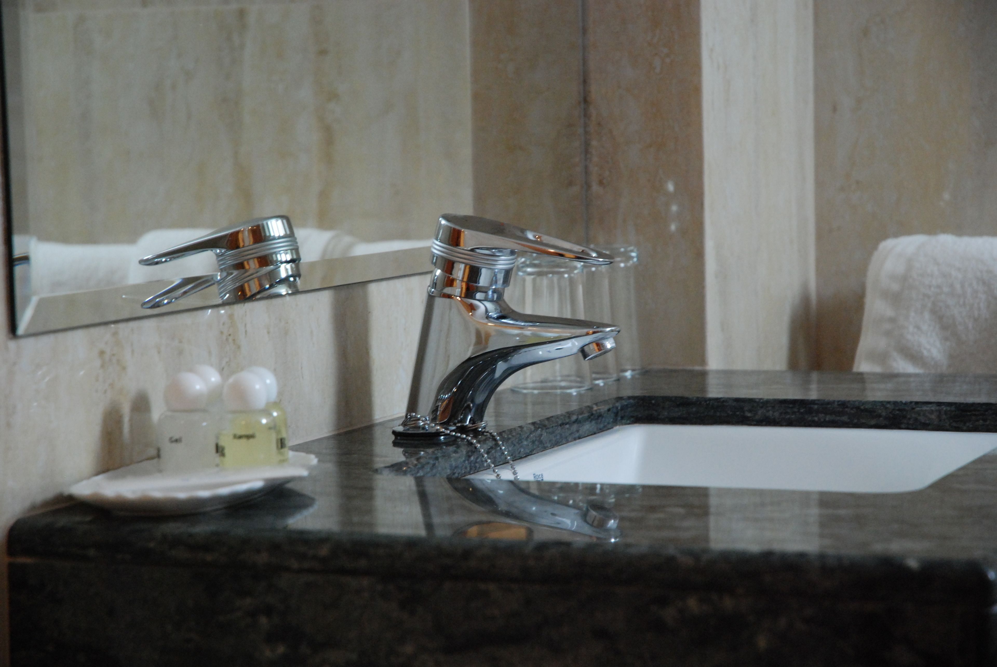 A bathroom with a modern sink, chrome faucets, and a mirror reflecting the room.