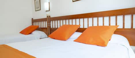 A hotel room with two beds, each with white bedding and orange pillows.