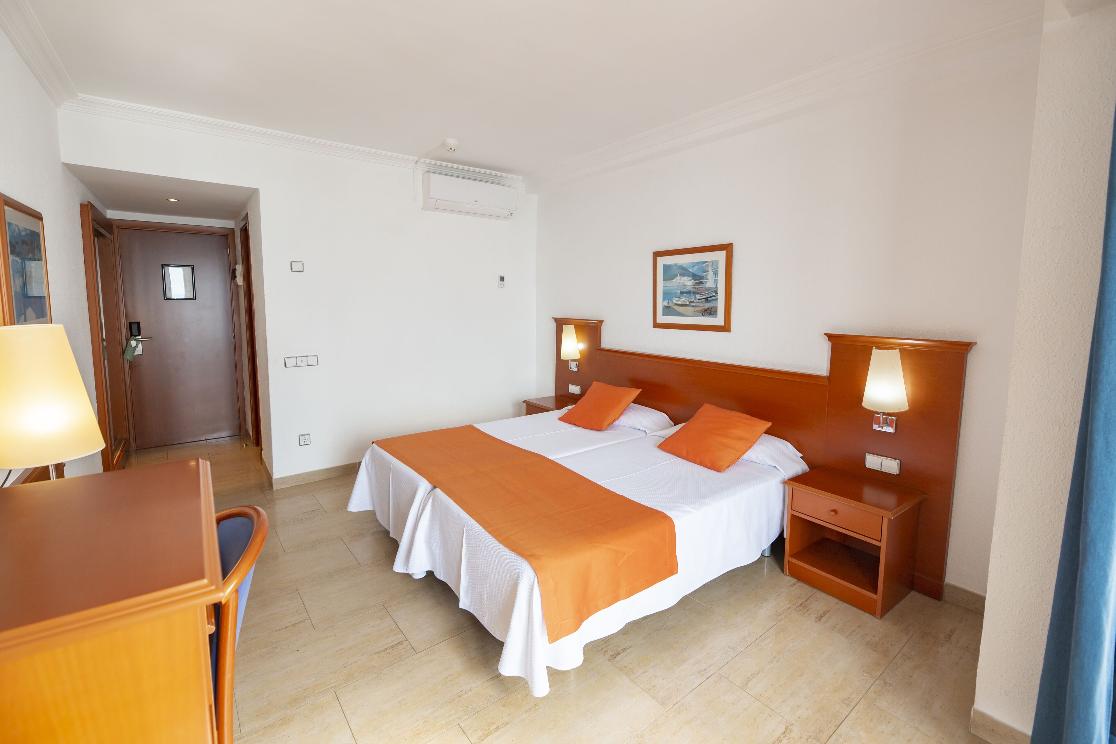 Een hotelkamer met een groot bed, twee nachtkastjes met lampen, een bureau en een stoel.