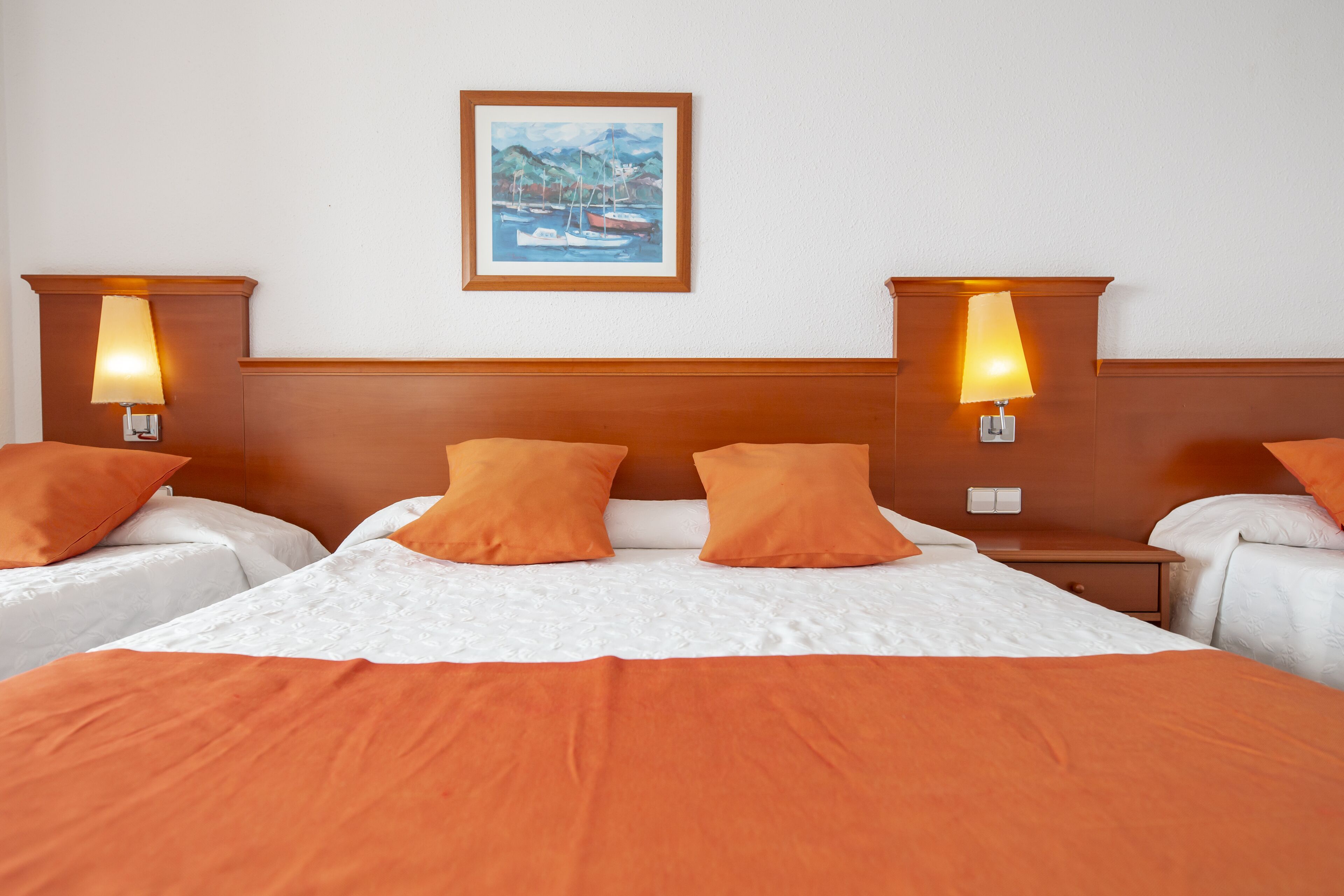 Una habitación de hotel con una cama grande, dos mesitas de noche y dos lámparas de pared.