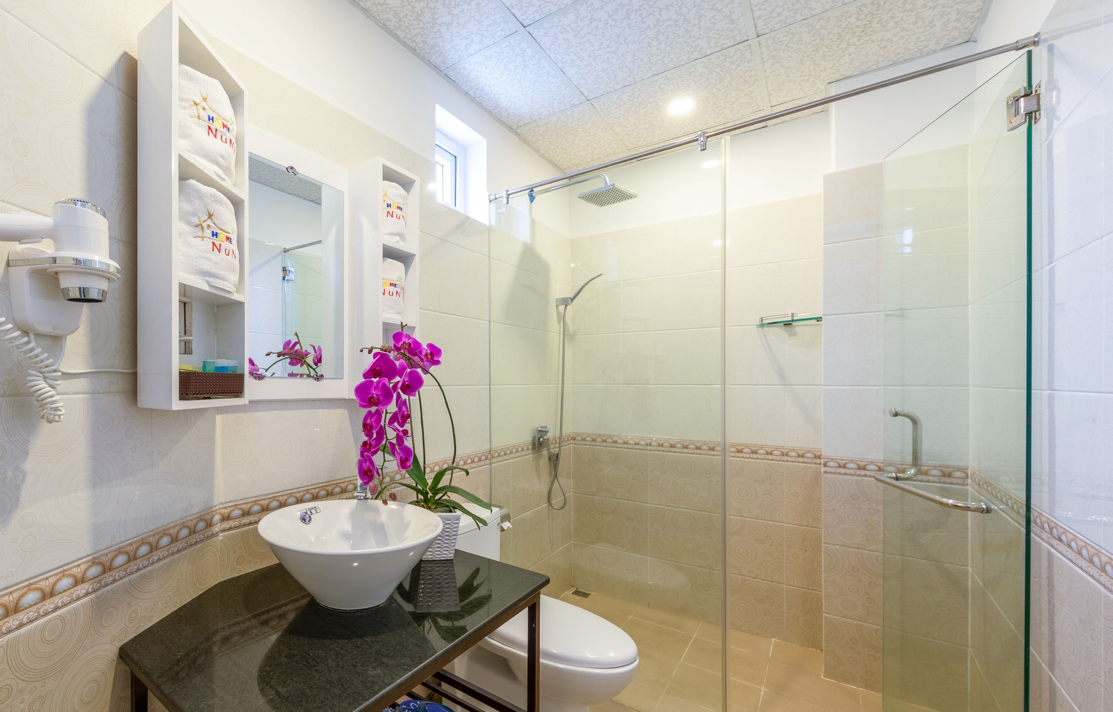 A bathroom with a glass-enclosed shower, a white sink, and a mirror above it.
