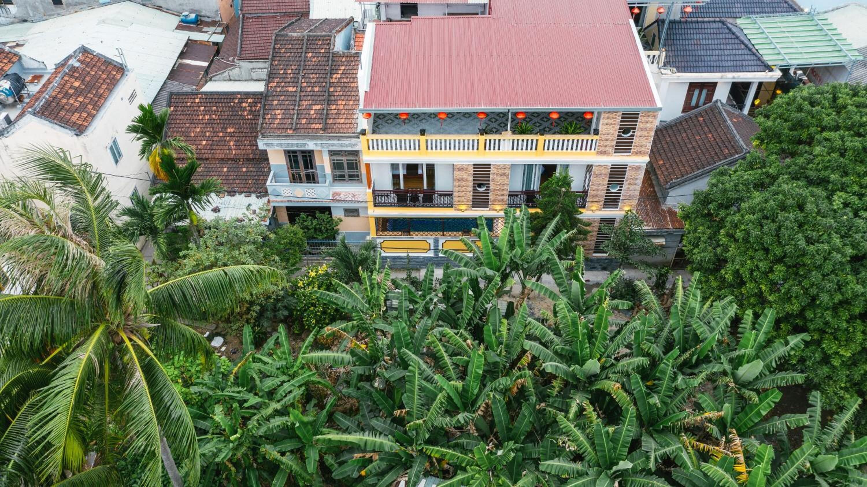A multi-story building with a red roof, surrounded by dense tropical vegetation.