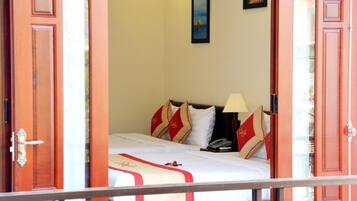 A hotel room with a bed, a nightstand, a lamp, and a painting on the wall.