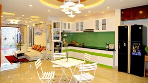 A modern kitchen with white cabinets, a green backsplash, and a black refrigerator. - NuNi Hoi An Homestay (Da Nang)