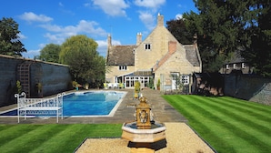 A stone house with a swimming pool, a fountain, and a well-maintained lawn. - River Nene Cottages (Peterborough)