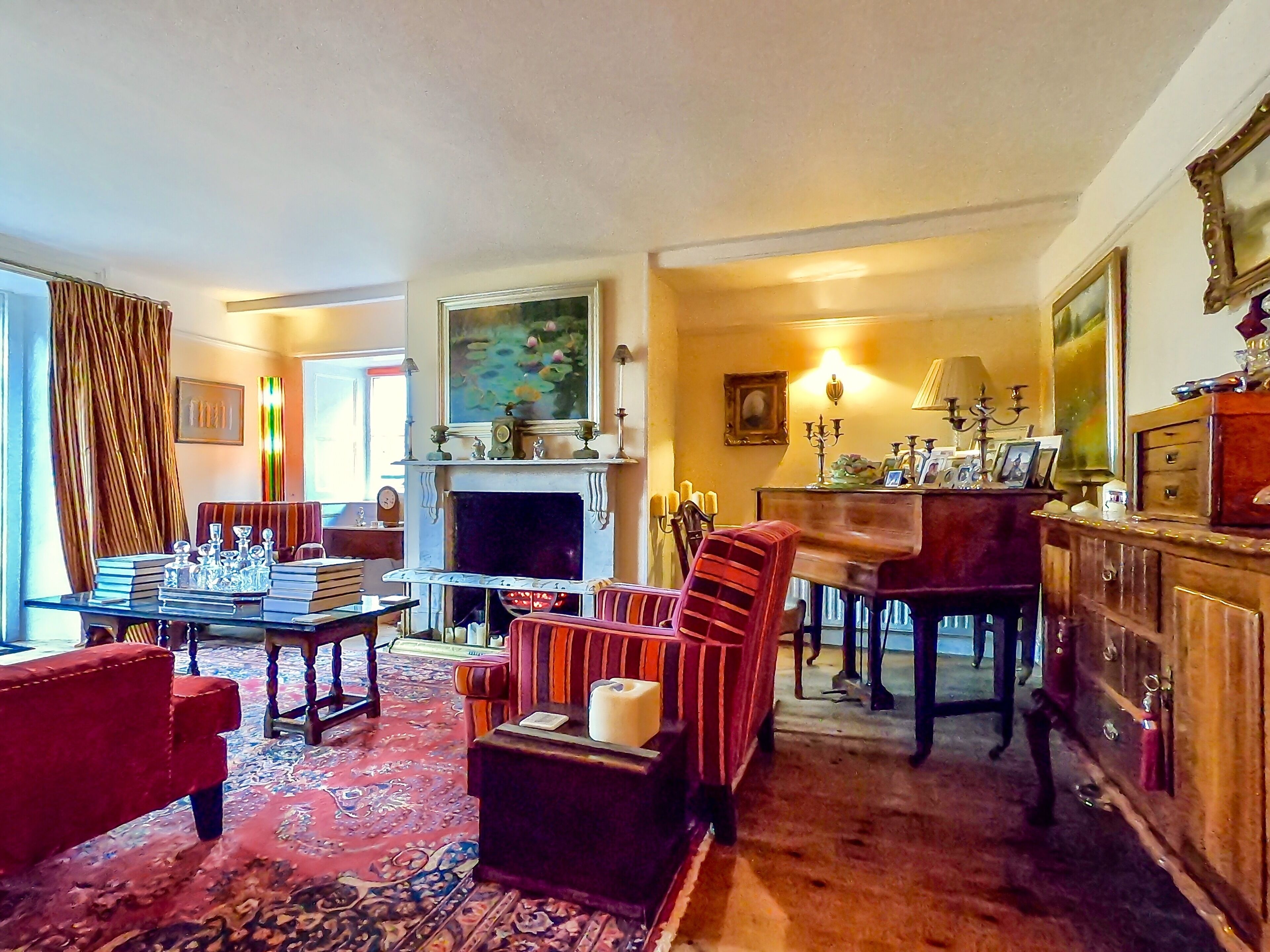 A cozy living room with a fireplace, a piano, and a red armchair.