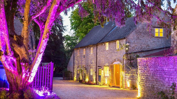 A stone building with a gravel driveway and a wooden gate. - River Nene Cottages (Peterborough)