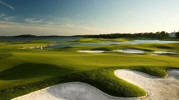 A golf course with sand bunkers, water hazards, and a flagstick.