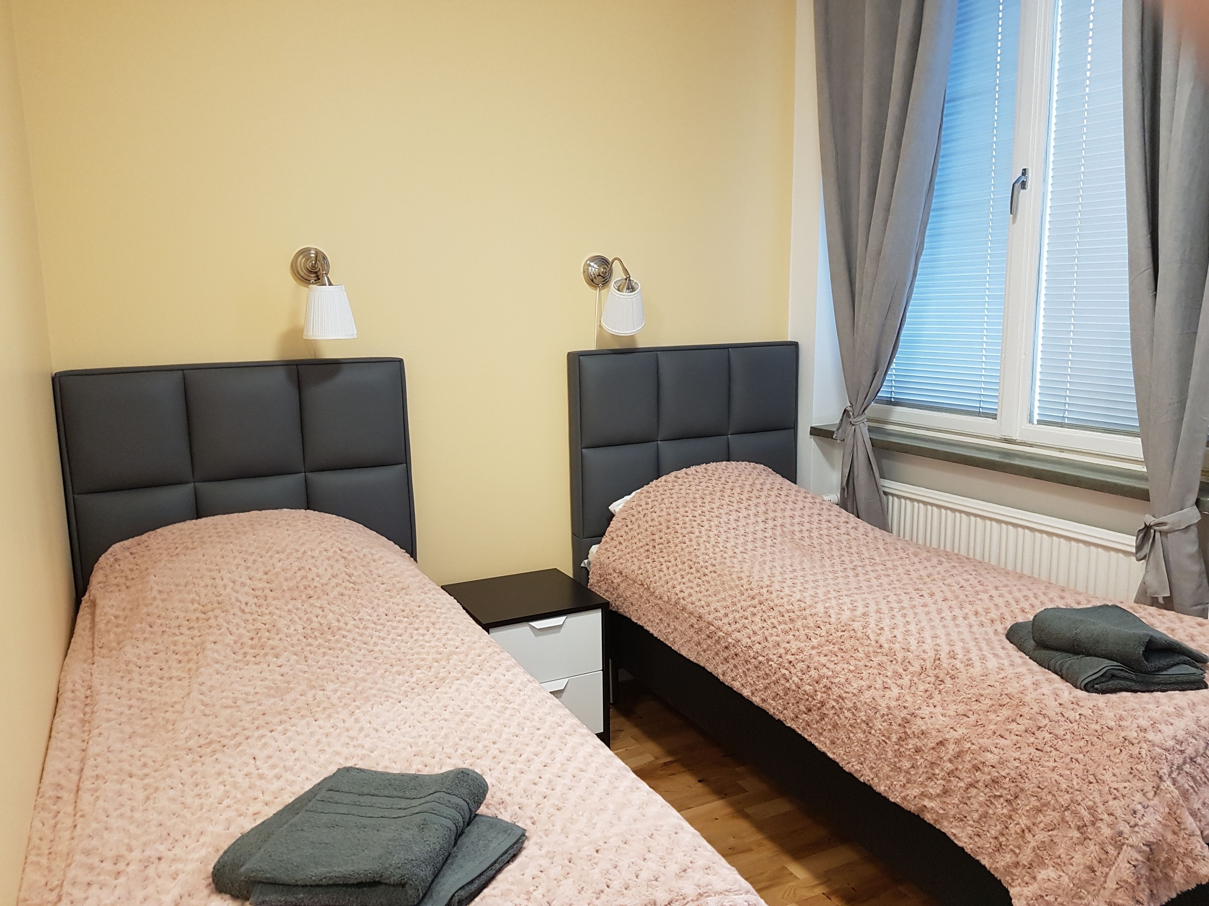 A twin room with two beds, each with a headboard and a bedside table.