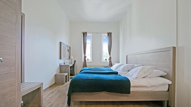 A modern bedroom with a wooden bed, a desk, and a chair. - Hotell Kringelstaden (Sodertalje)