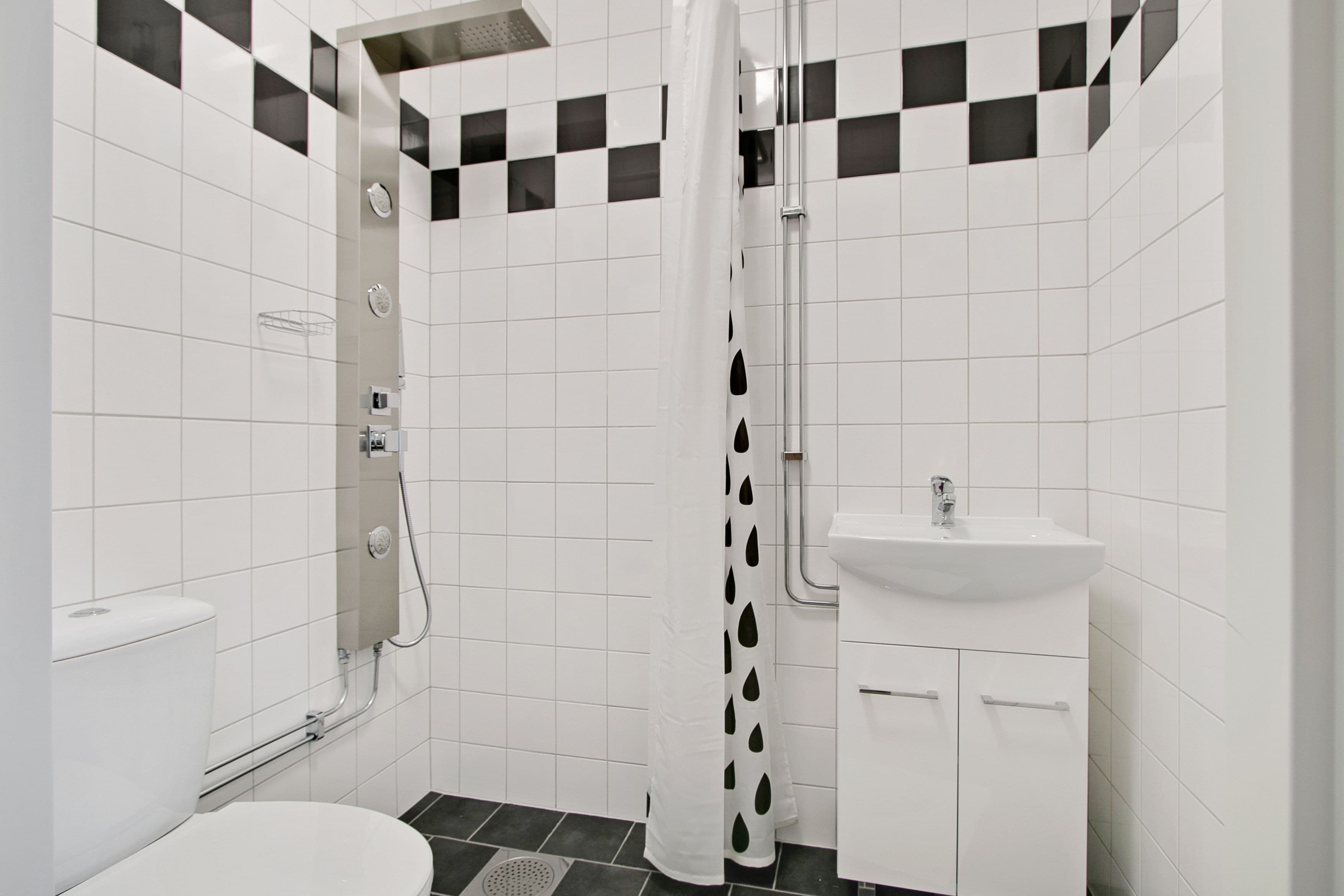 A bathroom with a toilet, shower, and sink.